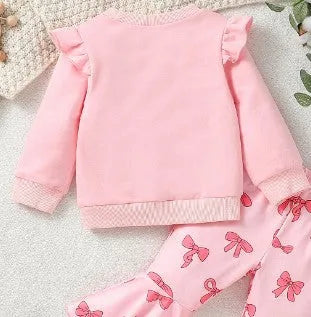Pink two-piece girls' suit with long sleeve flounced sleeve knitted sweater, printed bow, and flared pants on white background