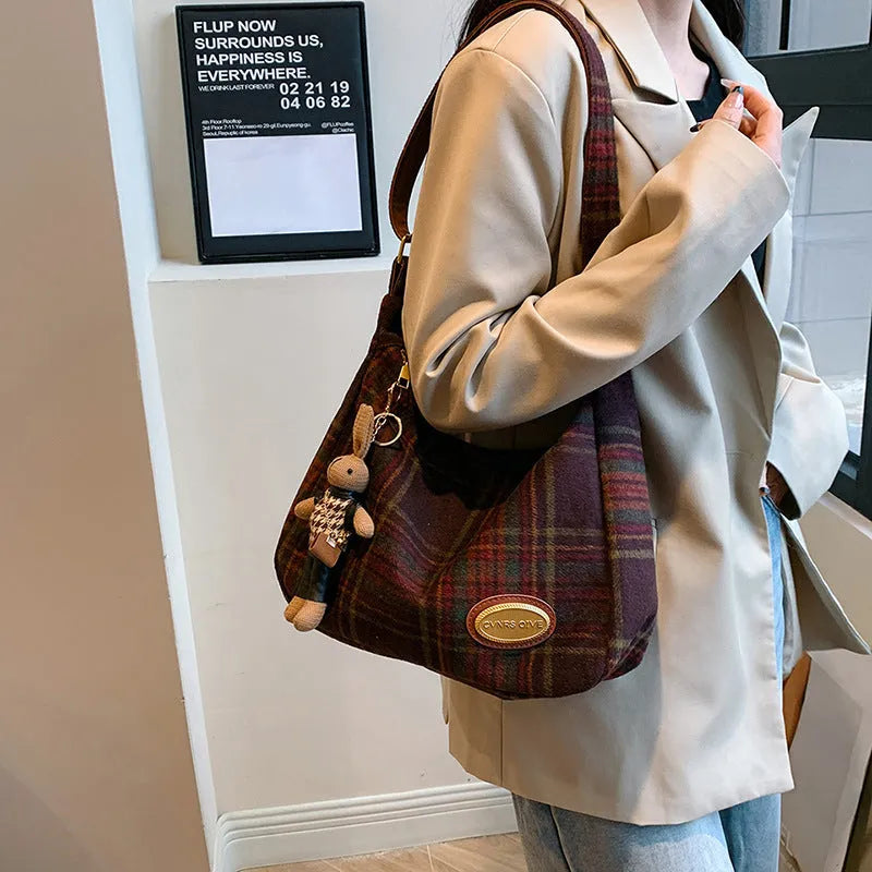 Red women's large wool shoulder bag with pendant on a table, showing square shape and sewing detail.