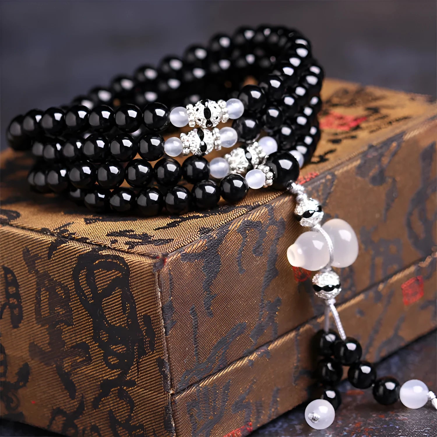 Natural red and black agate stone beaded bracelet with 108 geometric beads on a wrist.