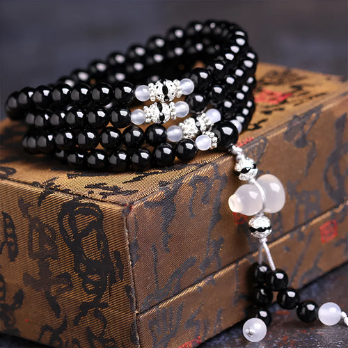 Natural red and black agate stone beaded bracelet with 108 geometric beads on a wrist.