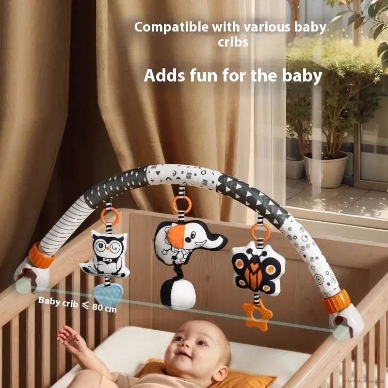 Baby lathe clip hanging plush toy in black and white with pull vibration teether, attached to a cot