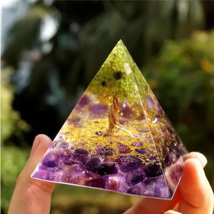 Clear epoxy resin pyramid ornament with natural crystal gravel inside on a wooden surface.
