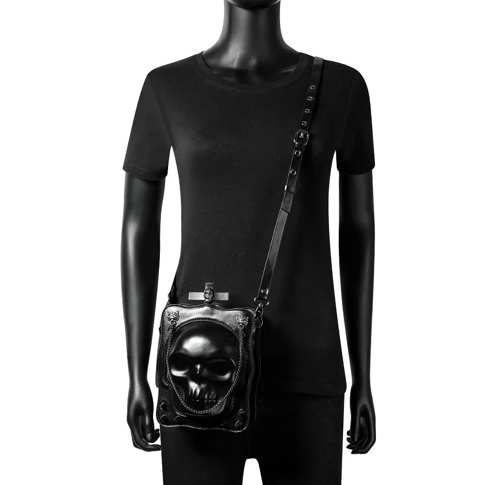 Black gothic crossbody bag with skull design, stitching, rivets, and chain details.