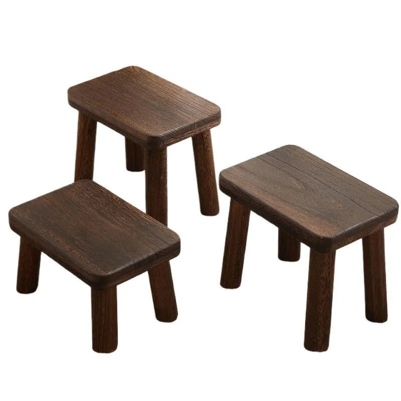 Solid wood distressed finish changing stool with bracket structure legs in a living room setting.