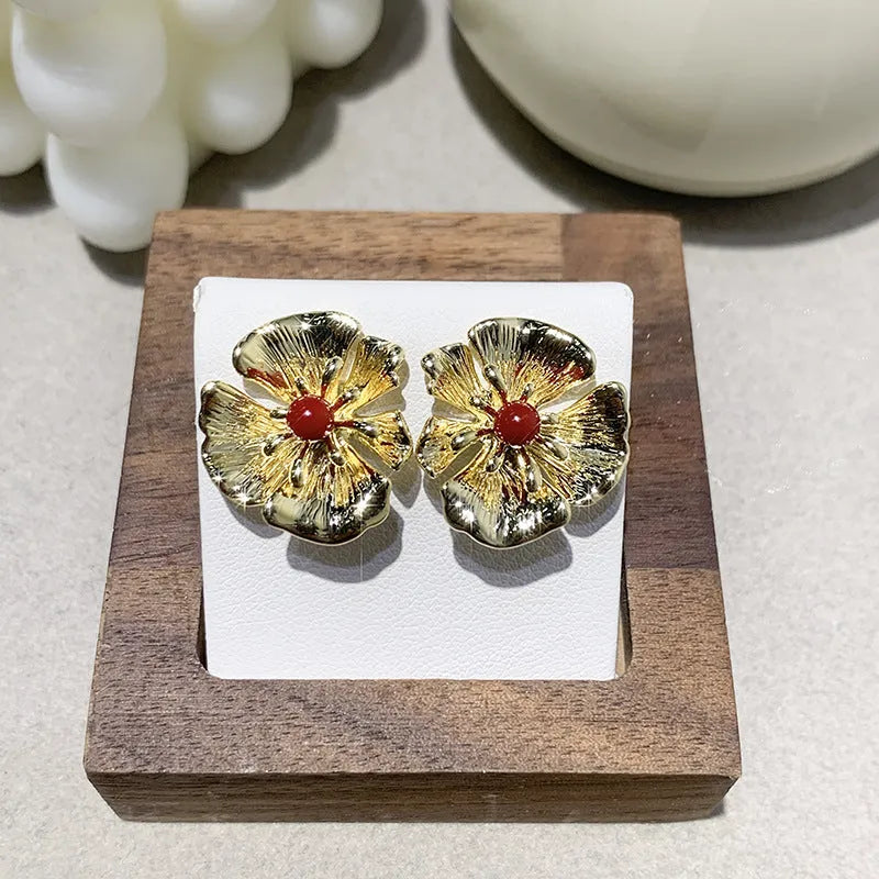 Pearl flower shaped metal earrings in red and white colour options on a grey background
