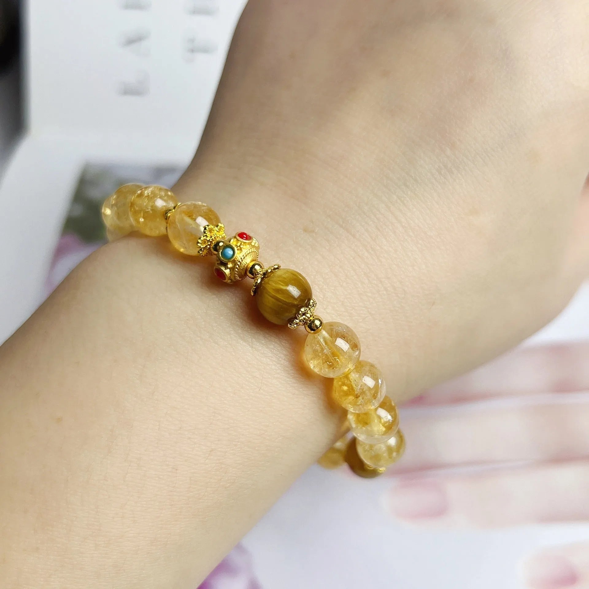 Women's citrine crystal bracelet with gold-plated flower tassel design on wrist.