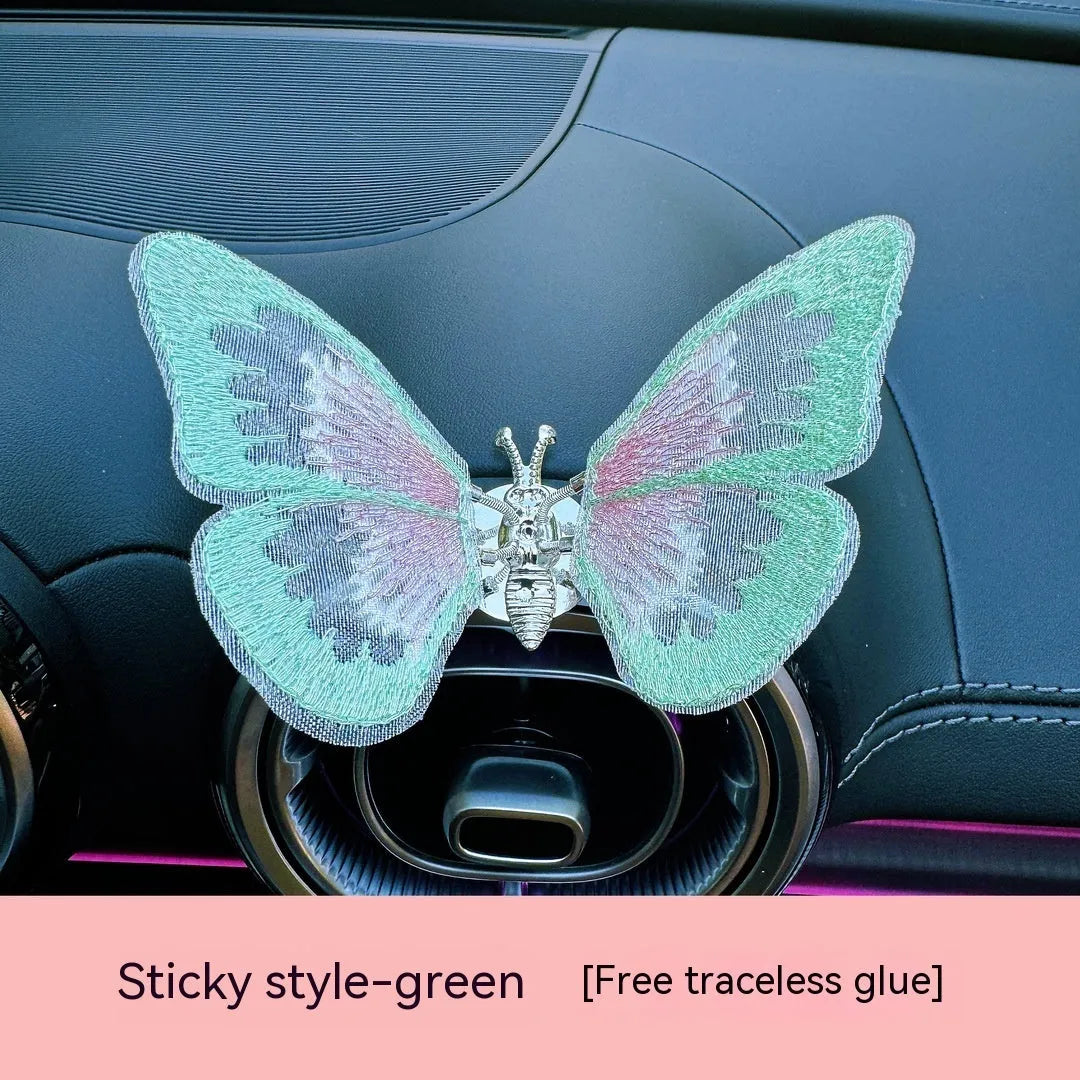 Fabric embroidered butterfly car air vent decoration in multiple colour options on a dashboard.