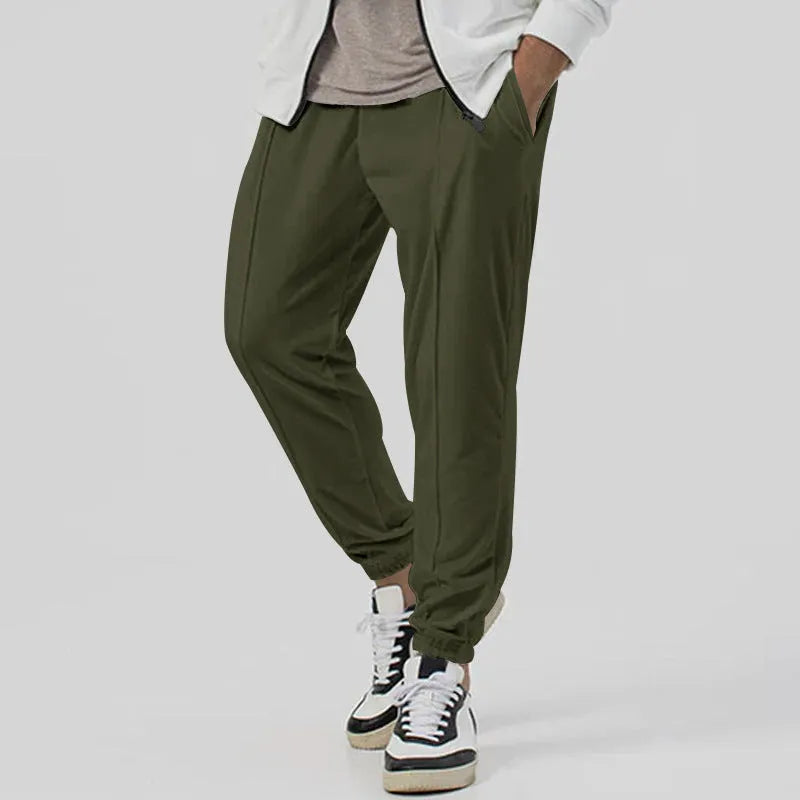 Man wearing grey loose tapered cotton blend track sweatpants with a straight leg.