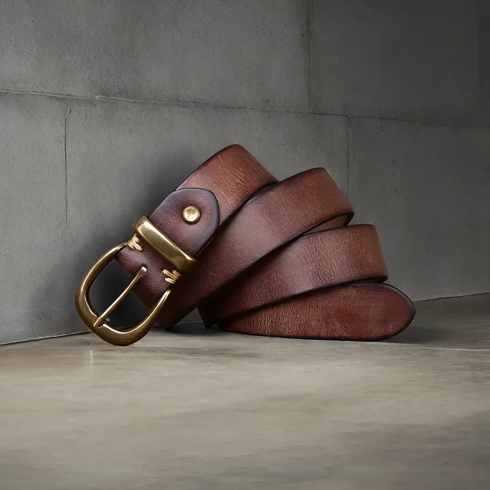 Men's black cattlehide leather jeans belt with a copper pin buckle on a wooden background.