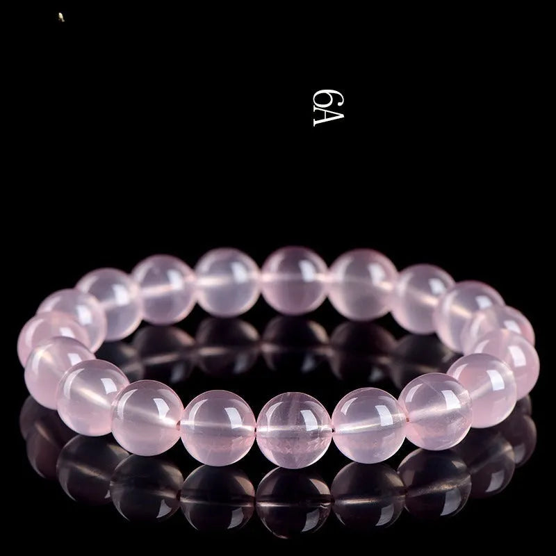 A polished natural starlight crystal round bead bracelet in pink, shown in a single circle design.