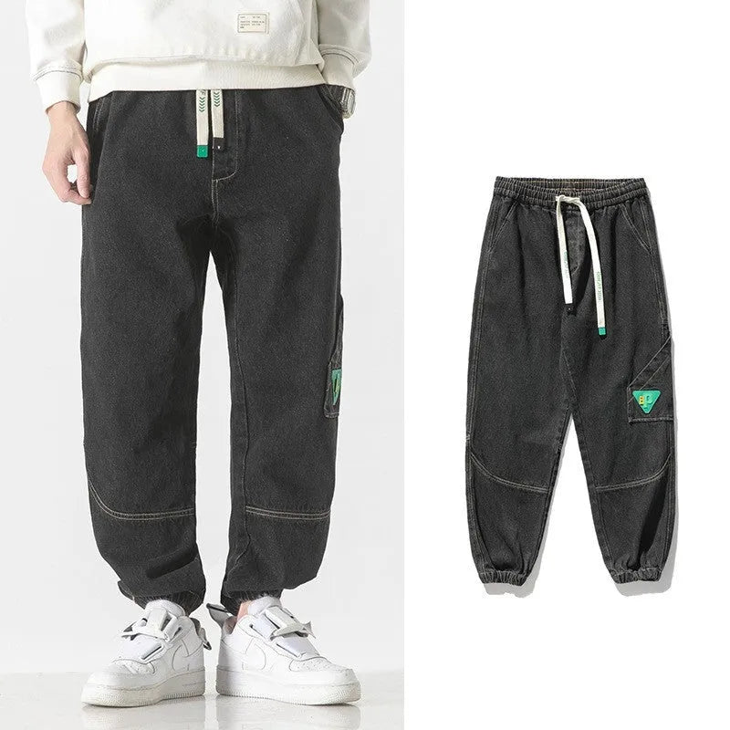Men's loose-fit tapered cotton trousers in black showing mid-waist design and tapered leg cut
