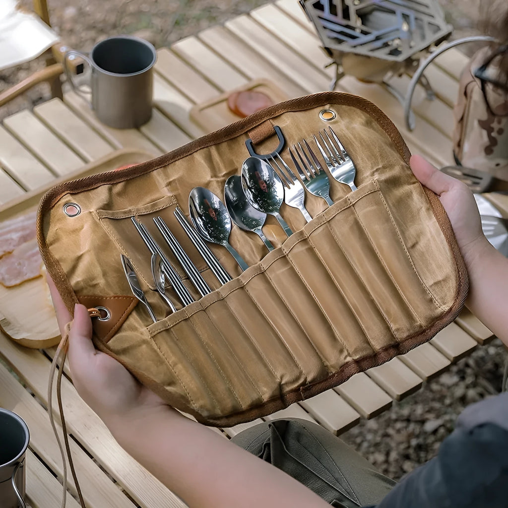 Green waxed canvas tableware storage bag containing wooden handle knives, forks, spoons, and chopsticks for outdoor use.