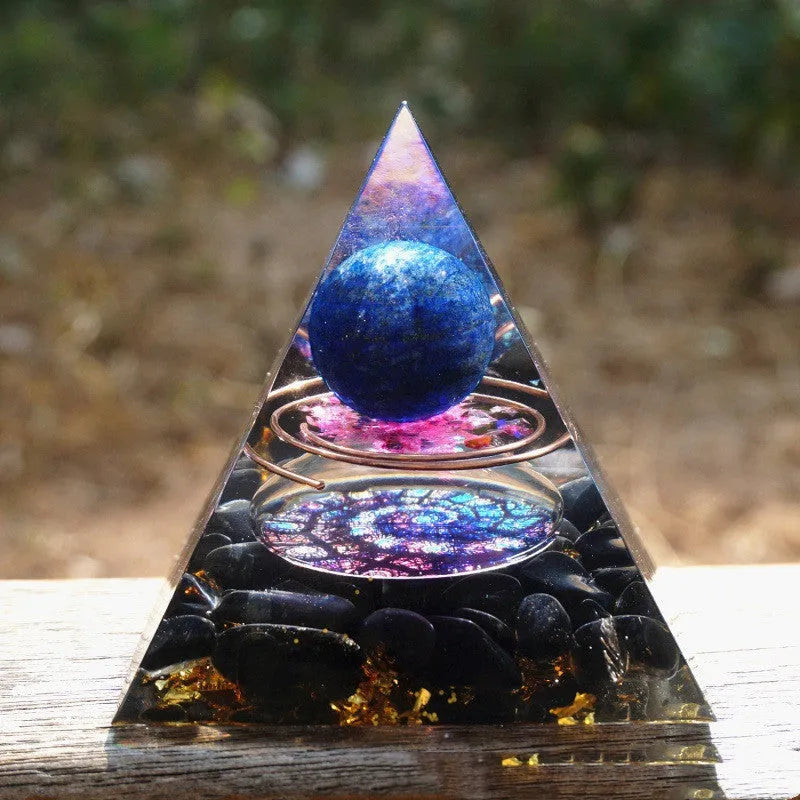 Clear epoxy resin pyramid ornament with natural crystal gravel inside on a wooden surface.