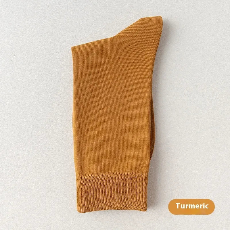 Five pairs of men's solid colour mid-calf socks made from combed cotton, shown in assorted shades.
