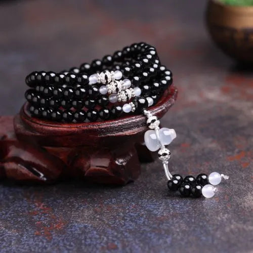 Natural red and black agate stone beaded bracelet with 108 geometric beads on a wrist.