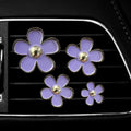 Set of four metal flower-shaped car vent aromatherapy clips in assorted colours