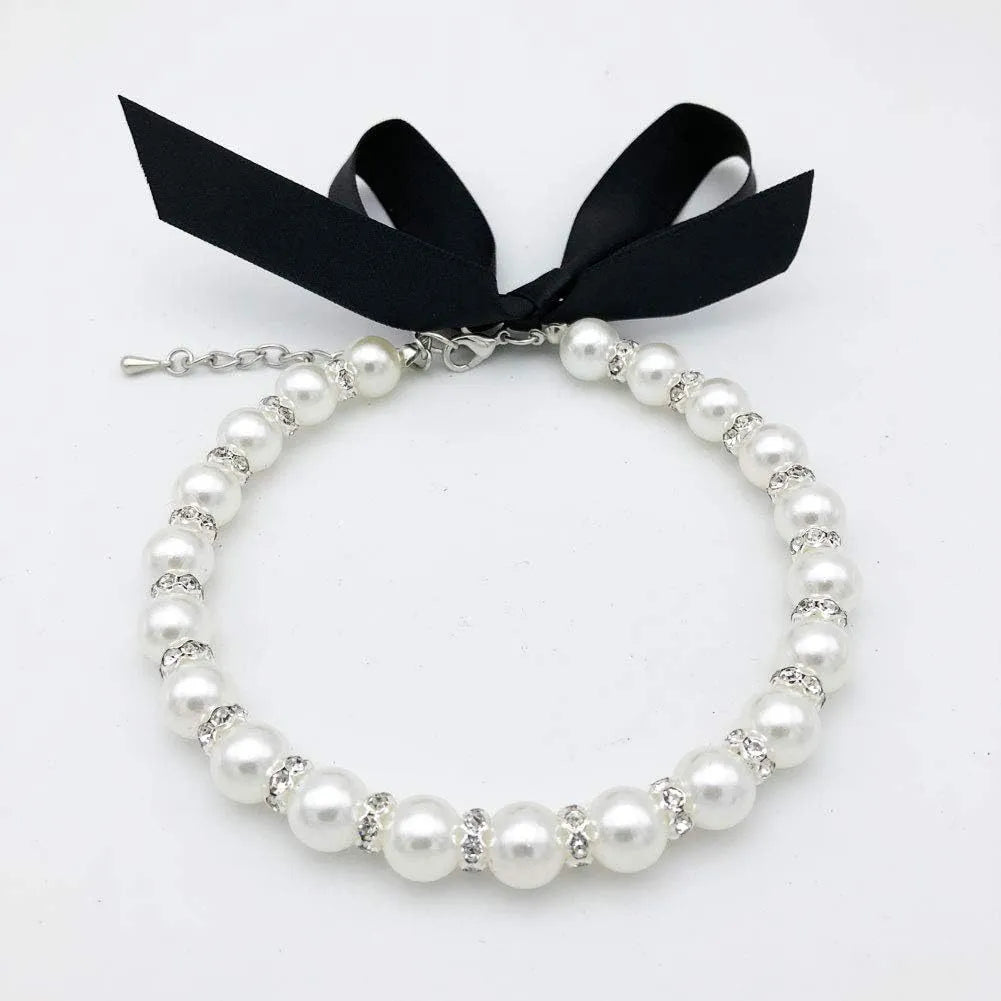 Small dog wearing adjustable diamond pearl necklace with rhinestones and ribbon bow in blue colour