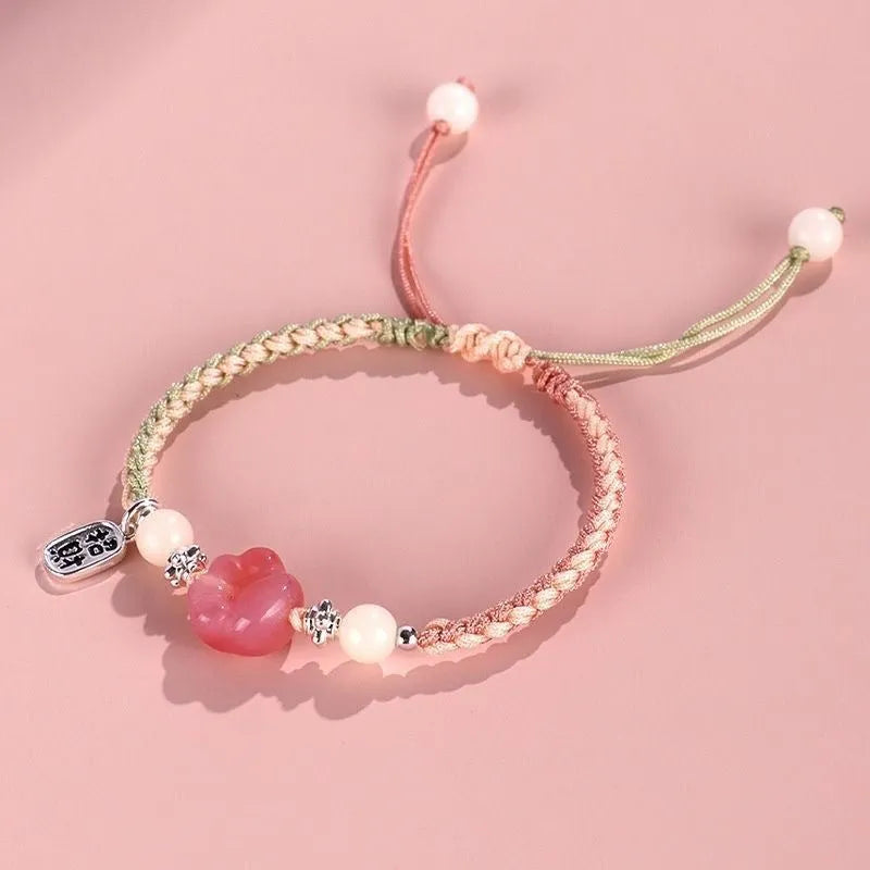 Red cat's paw glass bead on a handmade pink woven bracelet for couples.