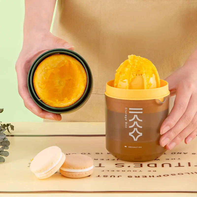 Green manual citrus juicer with lid and plunger, shown with lemons.