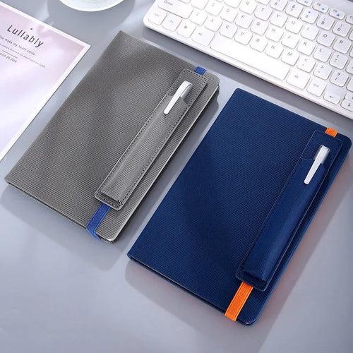 A5 faux leather notebook with pen insert and strap, open on a desk showing lined pages