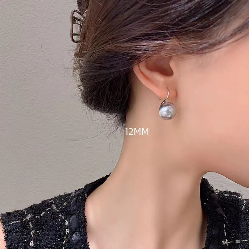 Silver round stud earrings with 12mm white shell pearl inlay on simple background