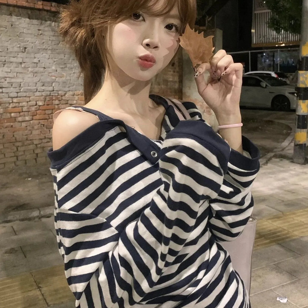 Dark blue oversized women's long-sleeved t-shirt with embroidery, stripes, and button detail on a hanger.