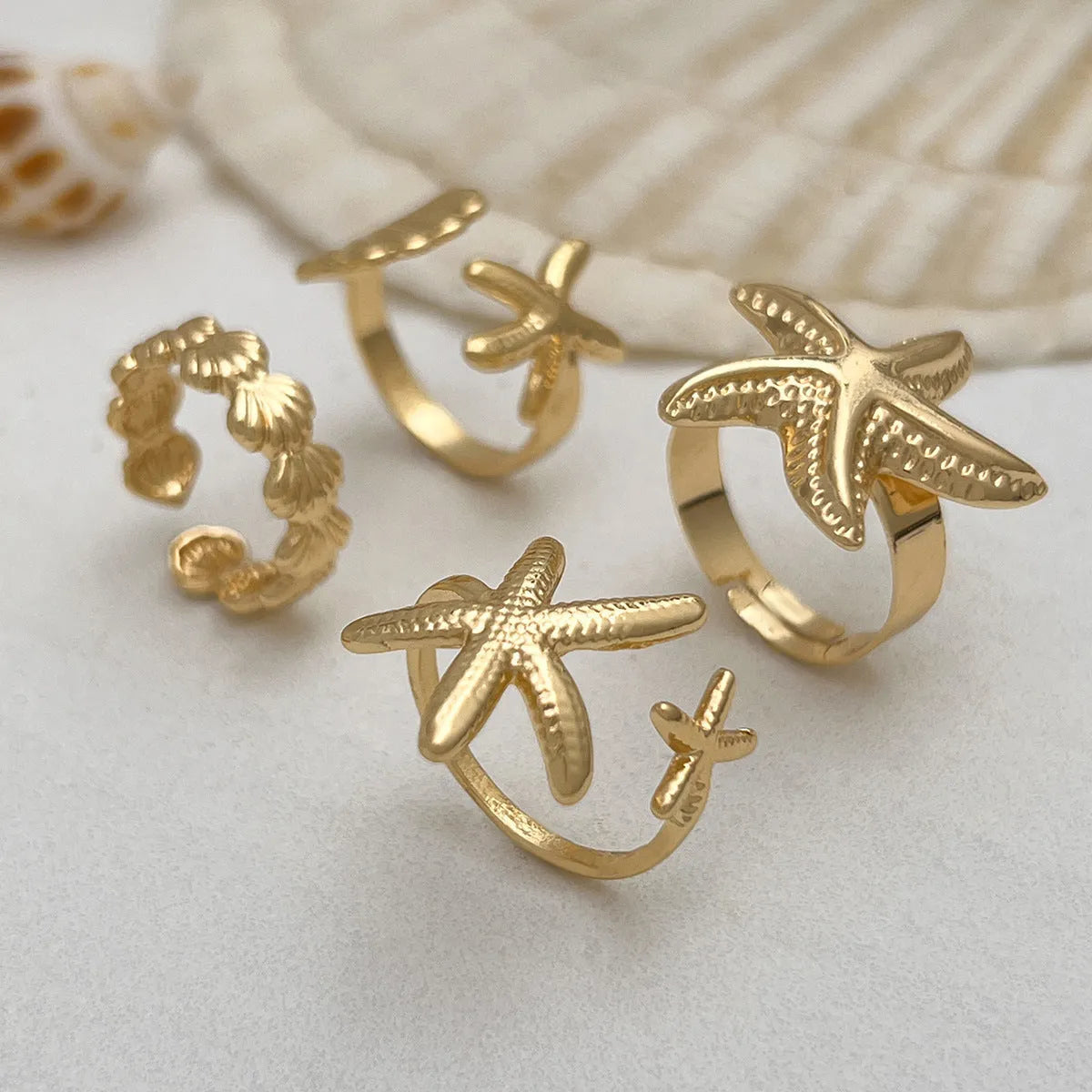 Women's irregular ocean shell ring set with starfish and fan shapes, light gold electroplated metal, 4-piece arrangement