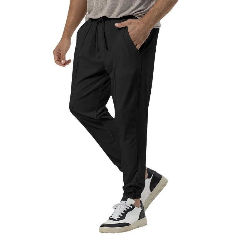 Man wearing grey loose tapered cotton blend track sweatpants with a straight leg.