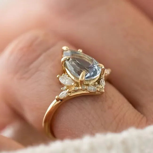 Gold alloy floral ring with aquamarine crystal centre on white background