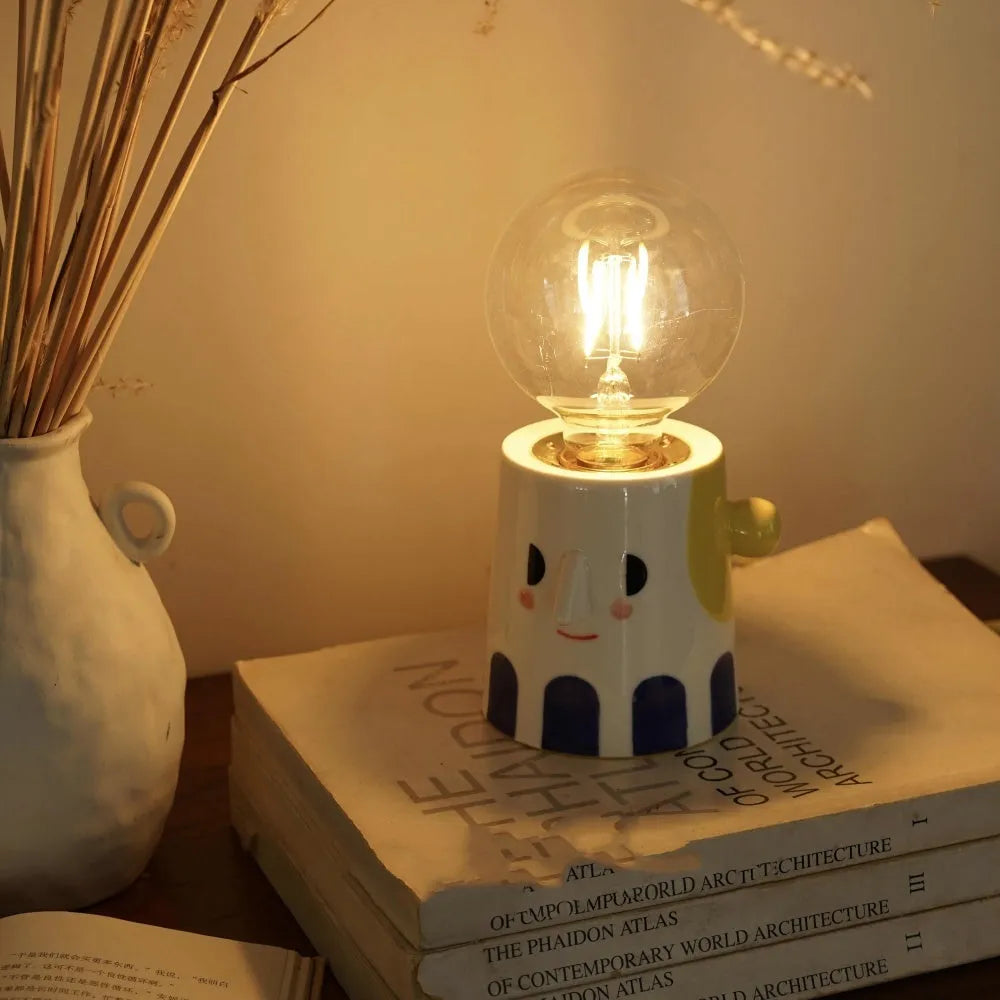 Handmade ceramic table lamp with a white ball headlight shade on a wooden table.