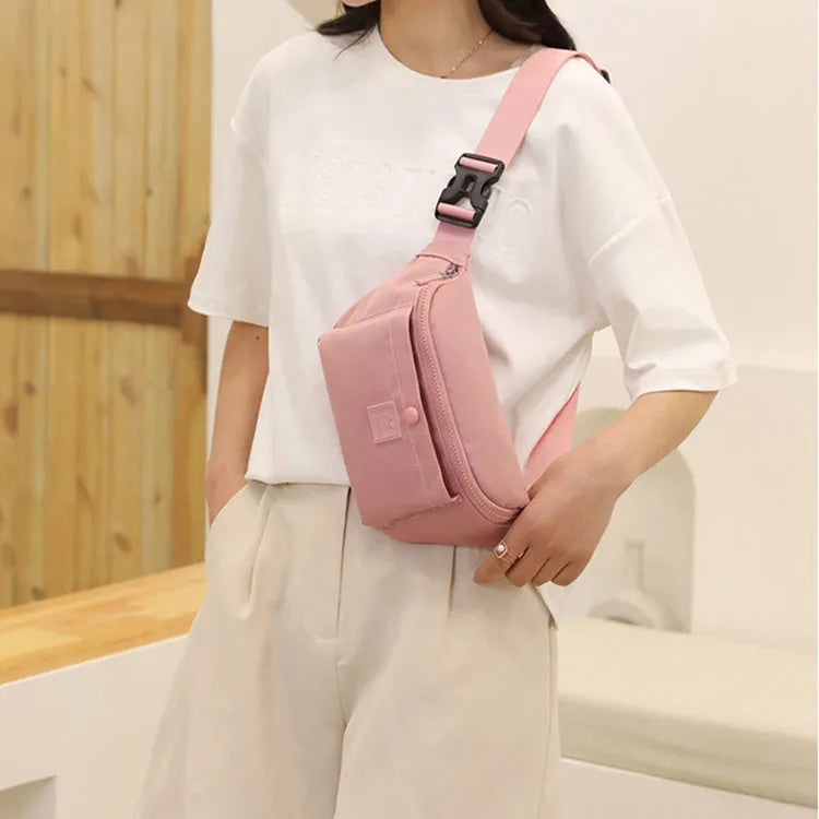 Women's nylon crossbody fanny pack in black with zippered compartments and letter detail.
