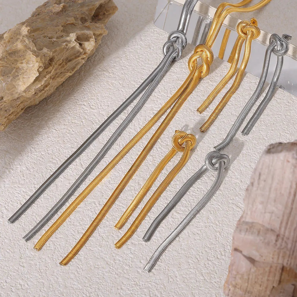 Gold long necklace with knotted tassel pendant and snake chain, shown with matching earrings.
