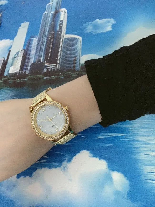 Golden mesh strap alloy electronic watch with round dial and world time GMT functions on a plain background