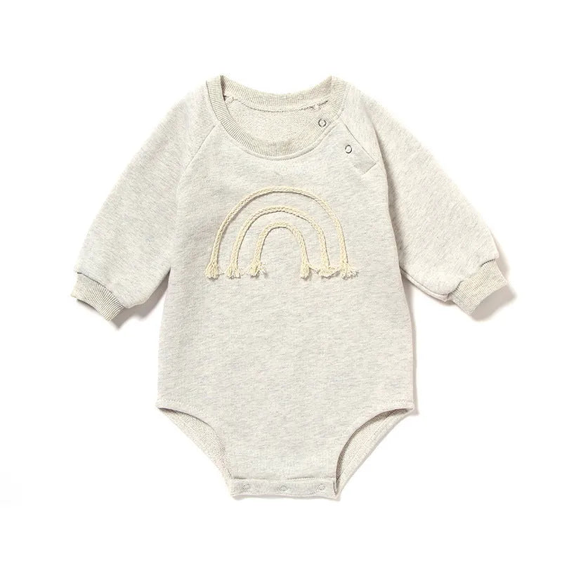 Long-sleeved waffle cotton baby romper in a neutral colour on a hanger, showing the triangular climbing front closure.