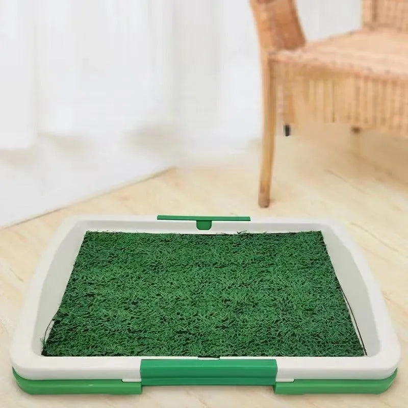 Green artificial grass indoor dog toilet tray with drainage holes and absorbent pads for puppy training.