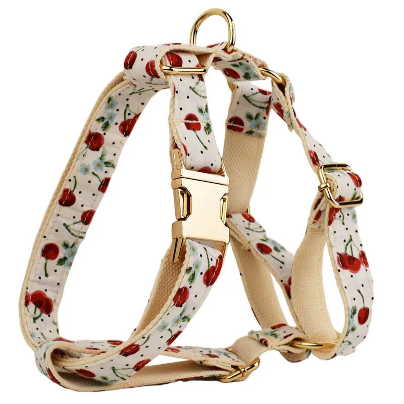 Red cherry print dog collar and leash set with light gold buckle, matching vest, bow, and poop bag holder.