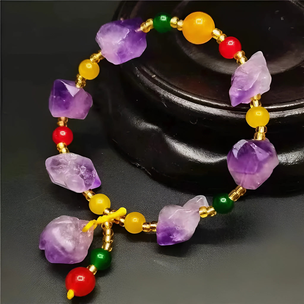 Women's natural amethyst bead bracelet with a fu character charm on a white background.