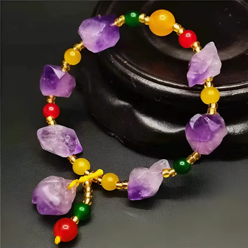 Women's natural amethyst bead bracelet with a fu character charm on a white background.