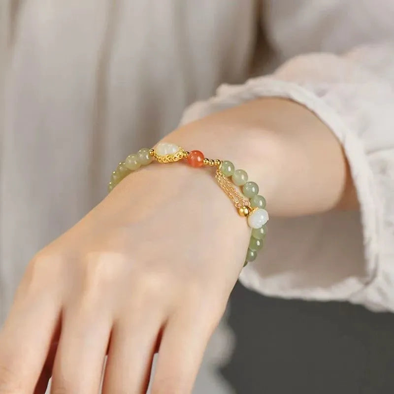Women's jade bracelet with gold-plated gourd charm and Fu character pendant on a 6mm bead.