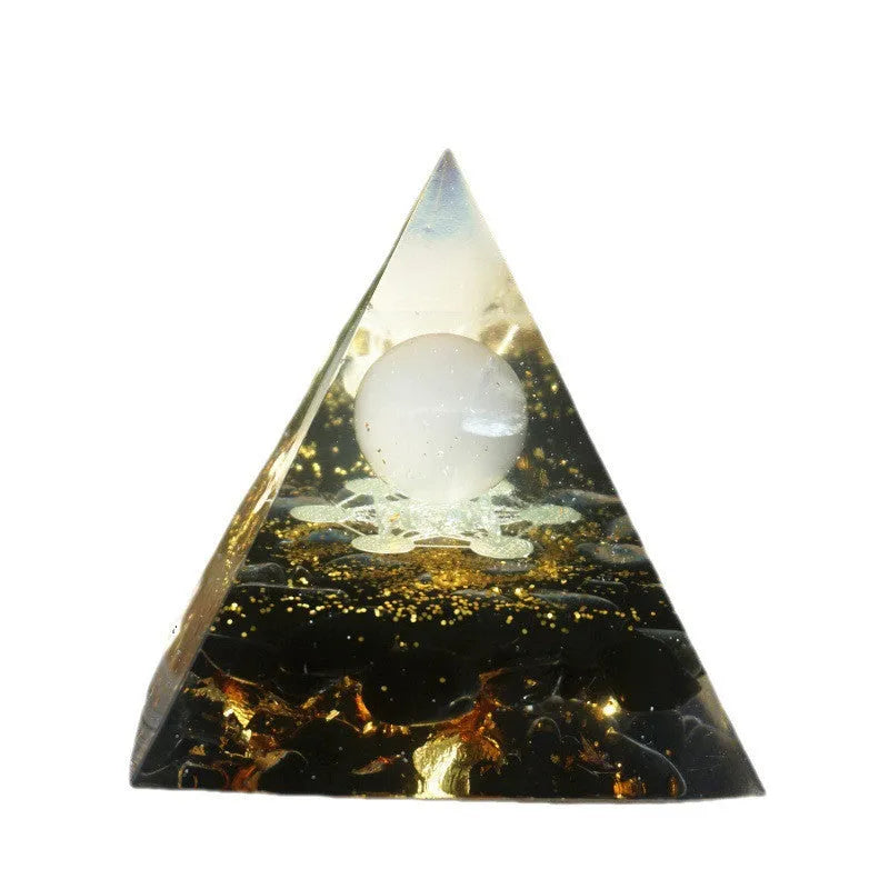 Clear epoxy resin pyramid ornament with natural crystal gravel inside on a wooden surface.