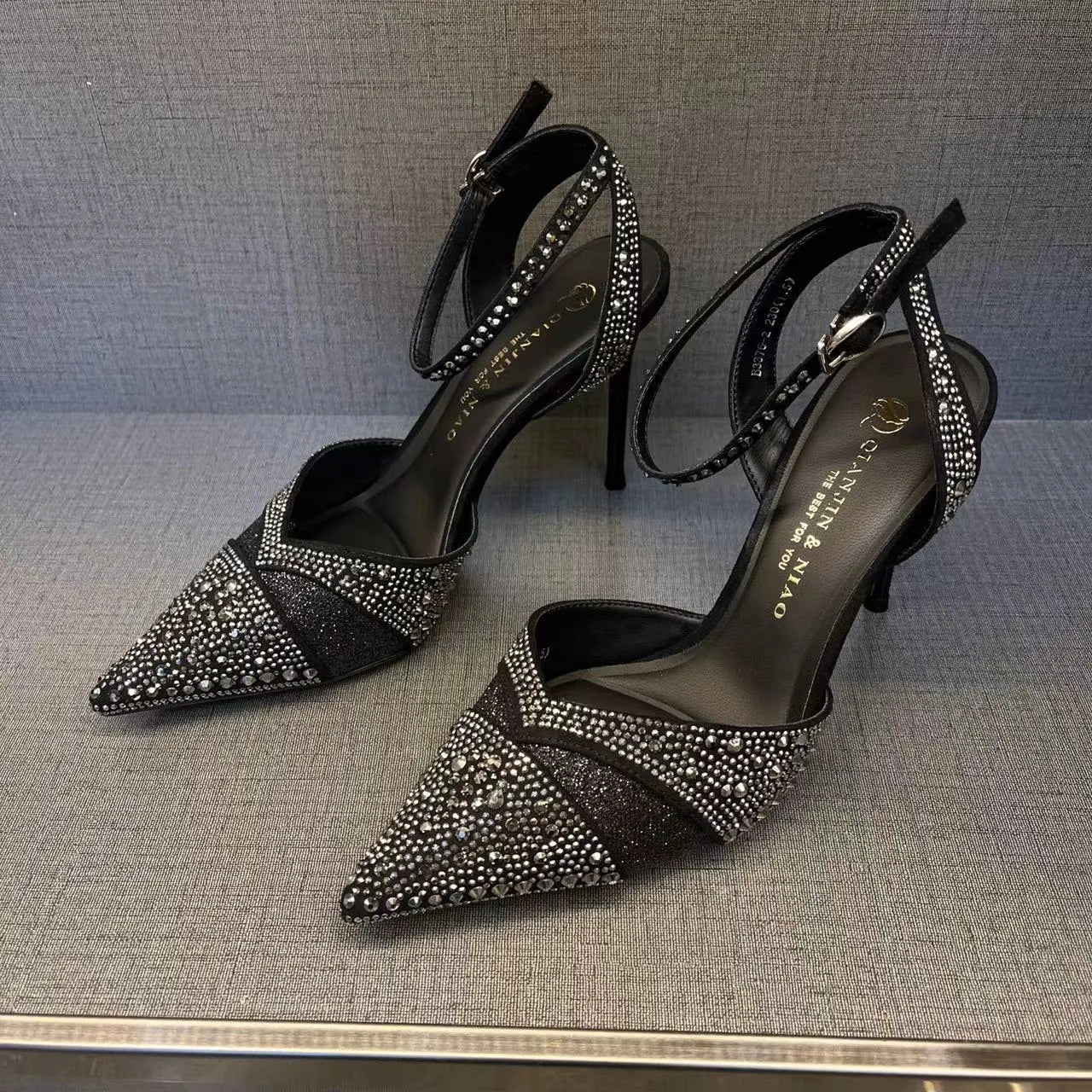 Black women's stiletto high heel shoe with a pointed toe and a bright red sole.