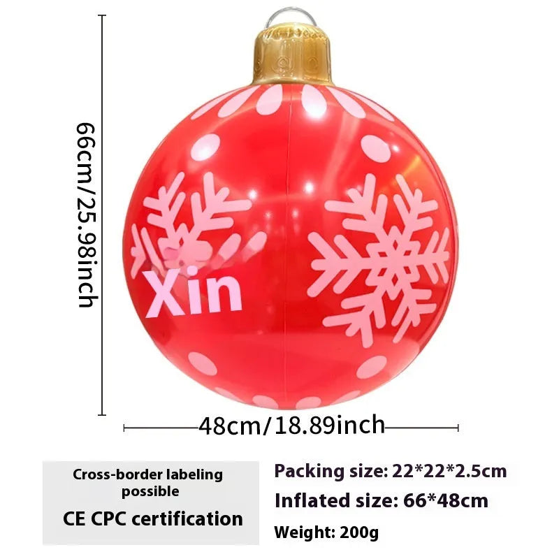 Large red inflatable Christmas ball with flashing lights displayed on a winter garden lawn.