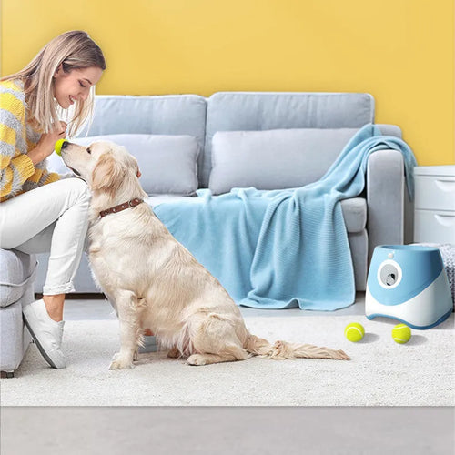 Blue automatic ball thrower with thermal sensor, three tennis balls, and USB charging cable on grass