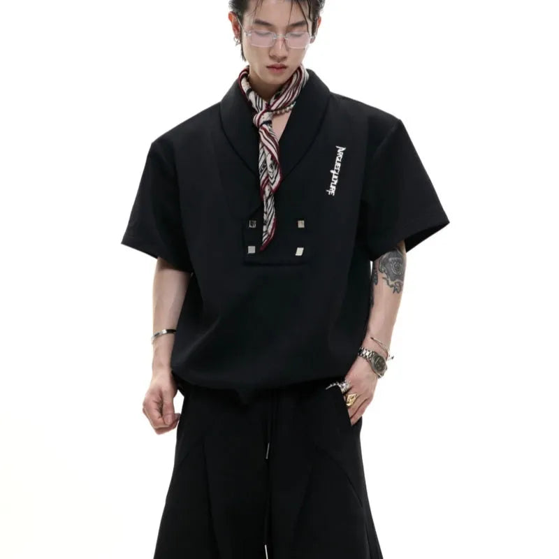 Men's dark grey cotton sports suit with V-neck top featuring padded shoulders and metal embellishments, paired with matching shorts.