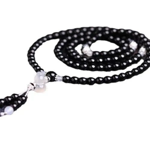 Natural red and black agate stone beaded bracelet with 108 geometric beads on a wrist.