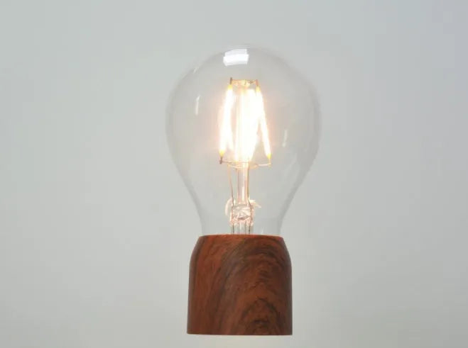 Magnetic levitation light bulb floating above its imitation wood base.