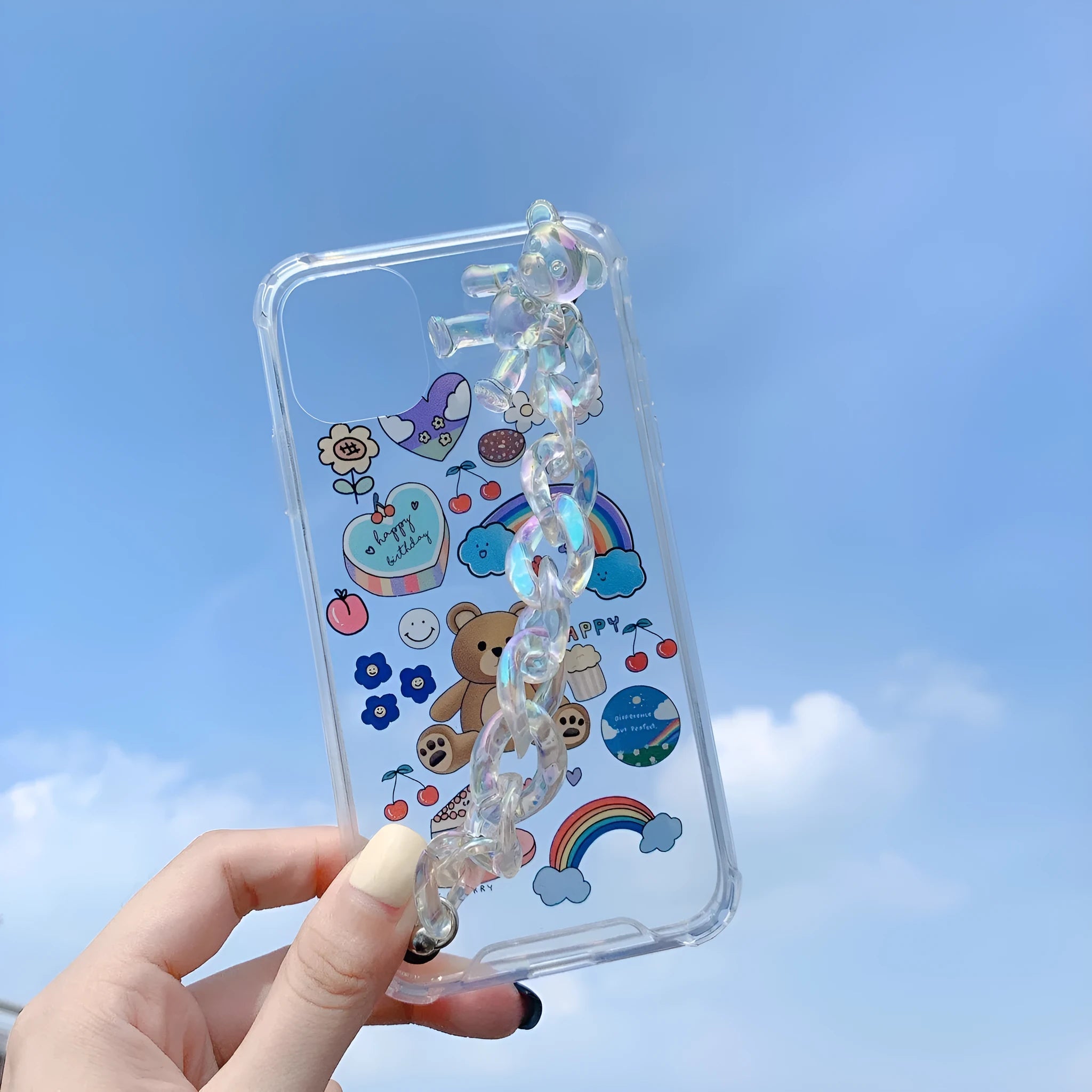 White iPhone case with a bear cartoon design and a silver chain with a bear pendant attached.