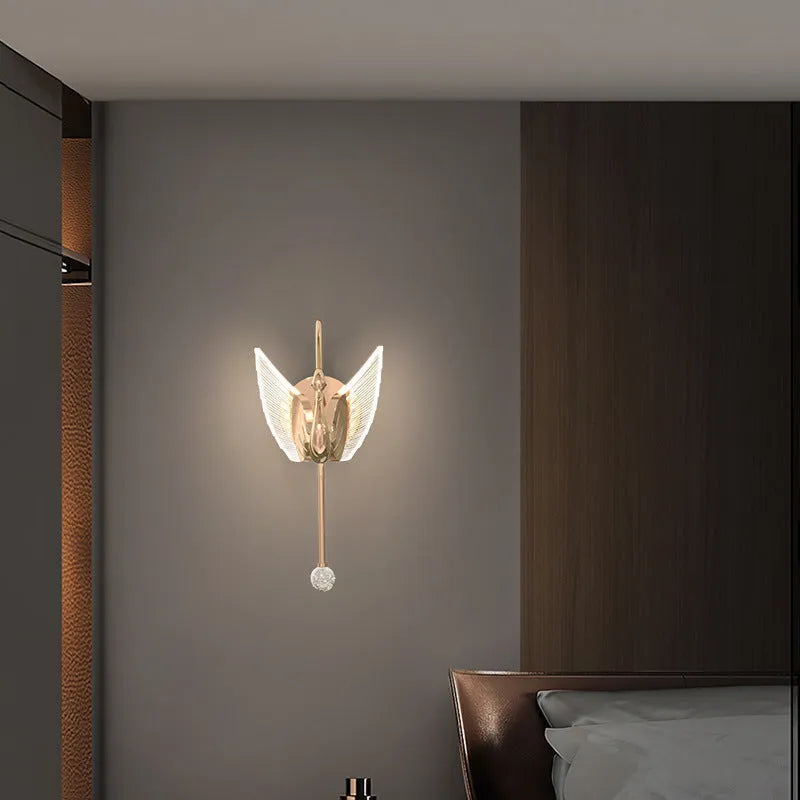 Modern gold swan-shaped wall lamp with white acrylic shade mounted on a wall.