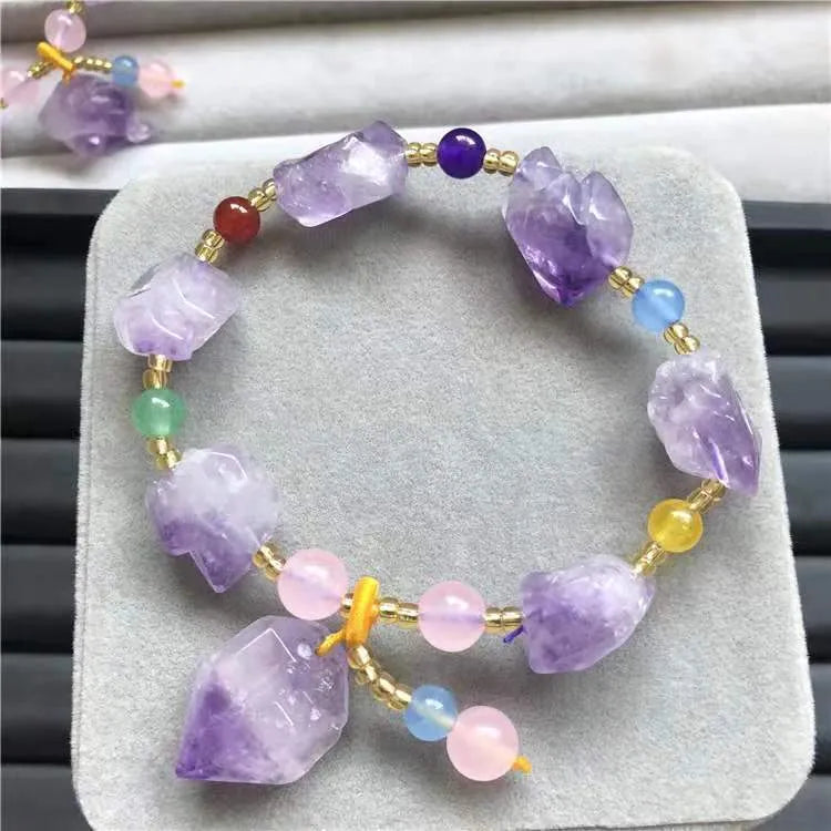 Women's natural amethyst bead bracelet with a fu character charm on a white background.