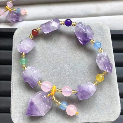 Women's natural amethyst bead bracelet with a fu character charm on a white background.